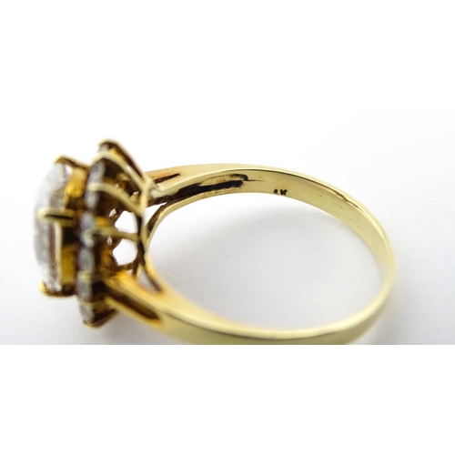 716 - A yellow metal dress ring set with central white stone bordered by further white stones. Ring size a... 