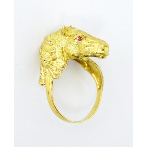 721 - A Continental gold ring with horse head decoration set with ruby stone eyes. Ring size approx. P