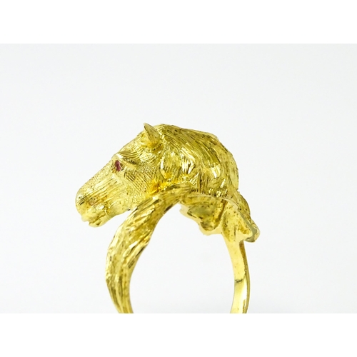 721 - A Continental gold ring with horse head decoration set with ruby stone eyes. Ring size approx. P