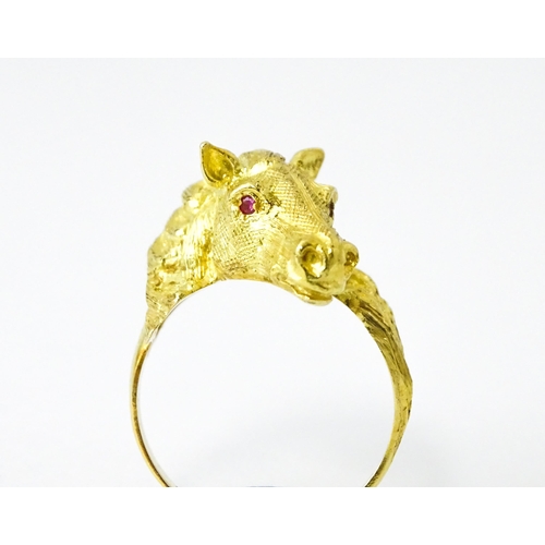 721 - A Continental gold ring with horse head decoration set with ruby stone eyes. Ring size approx. P