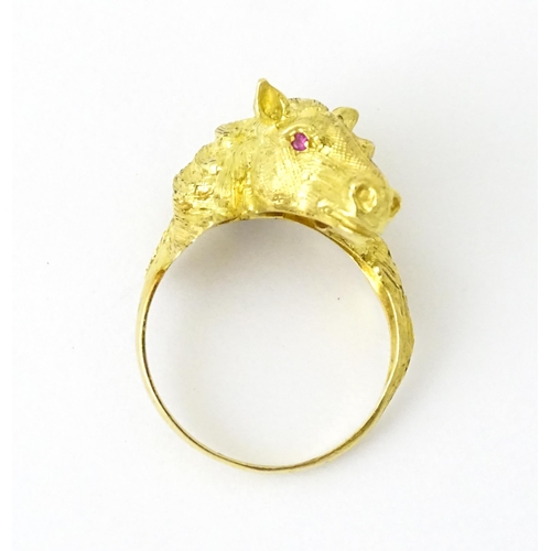 721 - A Continental gold ring with horse head decoration set with ruby stone eyes. Ring size approx. P