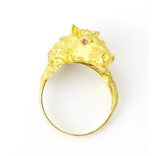 721 - A Continental gold ring with horse head decoration set with ruby stone eyes. Ring size approx. P