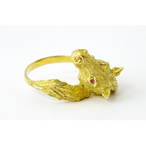 721 - A Continental gold ring with horse head decoration set with ruby stone eyes. Ring size approx. P