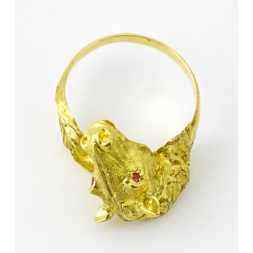 721 - A Continental gold ring with horse head decoration set with ruby stone eyes. Ring size approx. P