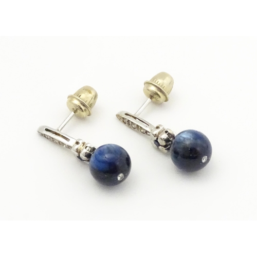 764 - A pair of white gold drop earrings set with diamonds, blue stone and bead detail. Approx. 3/4