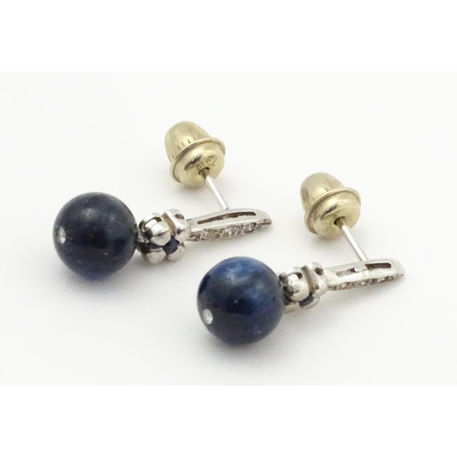 764 - A pair of white gold drop earrings set with diamonds, blue stone and bead detail. Approx. 3/4