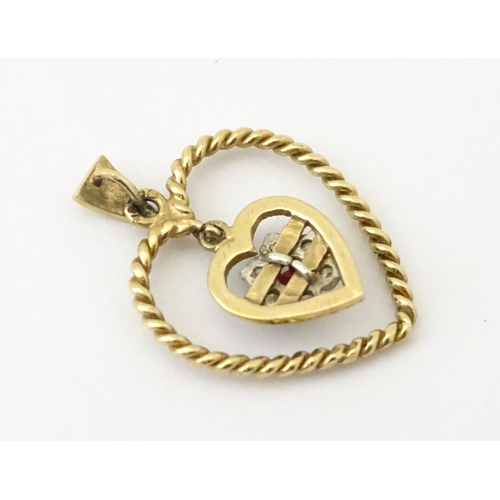 767 - A 9ct gold pendant of heart form with heart formed pendant to centre set with diamonds and red stone... 