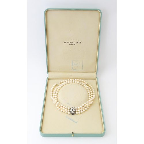 769 - A three strand pearl choker necklace with 14ct white gold clasp set with diamonds, sapphires, and pe... 