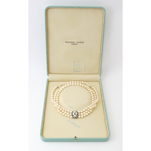 769 - A three strand pearl choker necklace with 14ct white gold clasp set with diamonds, sapphires, and pe... 