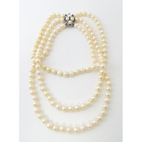 769 - A three strand pearl choker necklace with 14ct white gold clasp set with diamonds, sapphires, and pe... 