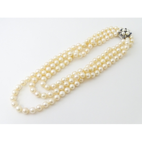 769 - A three strand pearl choker necklace with 14ct white gold clasp set with diamonds, sapphires, and pe... 