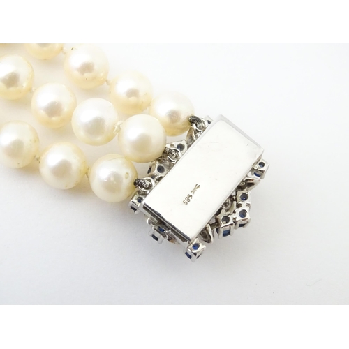 769 - A three strand pearl choker necklace with 14ct white gold clasp set with diamonds, sapphires, and pe... 