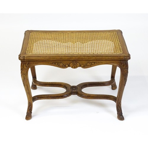 1541 - An early 20thC Louis XV style bergère stool with a caned top above four carved cabriole legs termina... 