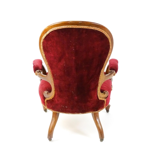 1564 - A Victorian mahogany open armchair with a deep buttoned spoon back above manchettes, and scrolled ar... 