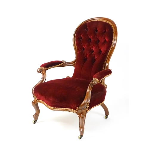 1564 - A Victorian mahogany open armchair with a deep buttoned spoon back above manchettes, and scrolled ar... 