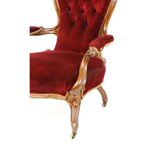 1564 - A Victorian mahogany open armchair with a deep buttoned spoon back above manchettes, and scrolled ar... 