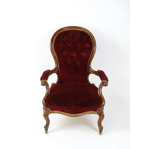 1564 - A Victorian mahogany open armchair with a deep buttoned spoon back above manchettes, and scrolled ar... 