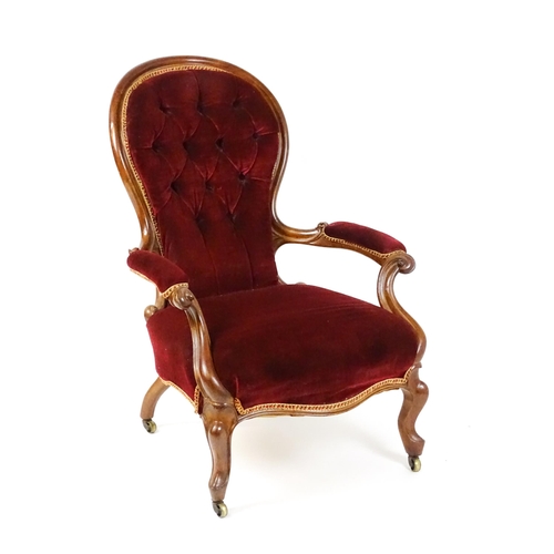 1564 - A Victorian mahogany open armchair with a deep buttoned spoon back above manchettes, and scrolled ar... 