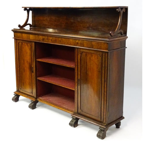 1597 - A 19thC rosewood bookcase with a moulded shelf raised on two scrolled brackets, the base having two ... 