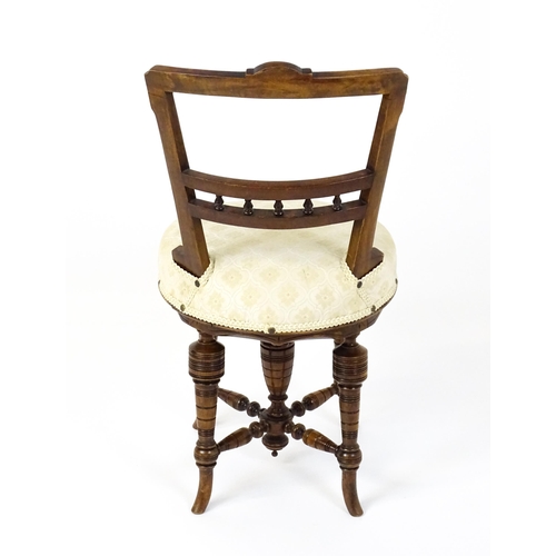 1599 - An Edwardian adjustable piano stool / chair with a floral carved top rail and turned finials to the ... 