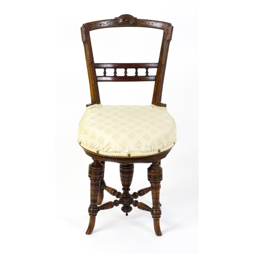 1599 - An Edwardian adjustable piano stool / chair with a floral carved top rail and turned finials to the ... 