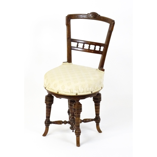 1599 - An Edwardian adjustable piano stool / chair with a floral carved top rail and turned finials to the ... 