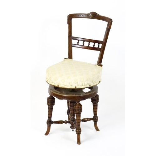 1599 - An Edwardian adjustable piano stool / chair with a floral carved top rail and turned finials to the ... 