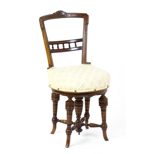 1599 - An Edwardian adjustable piano stool / chair with a floral carved top rail and turned finials to the ... 