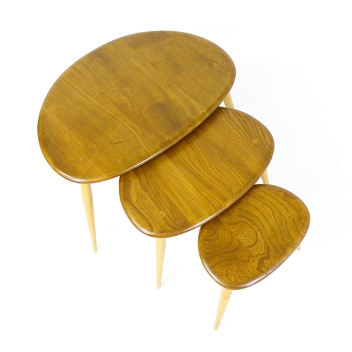 1638 - An Ercol nest of three elm pebble tables raised on turned tapering legs. 26