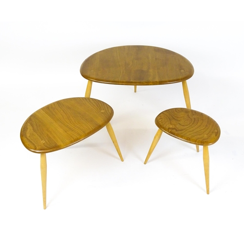 1638 - An Ercol nest of three elm pebble tables raised on turned tapering legs. 26