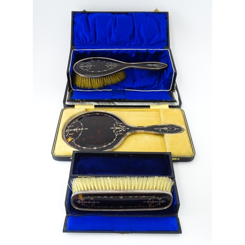 545 - Three individually cased silver dressing table items comprising two brushes and a hand mirror with t... 