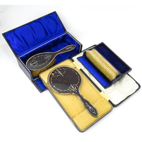 545 - Three individually cased silver dressing table items comprising two brushes and a hand mirror with t... 