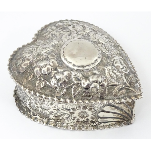 266 - A Victorian silver box of heart form with embossed floral decoration, the lid hinging open to reveal... 