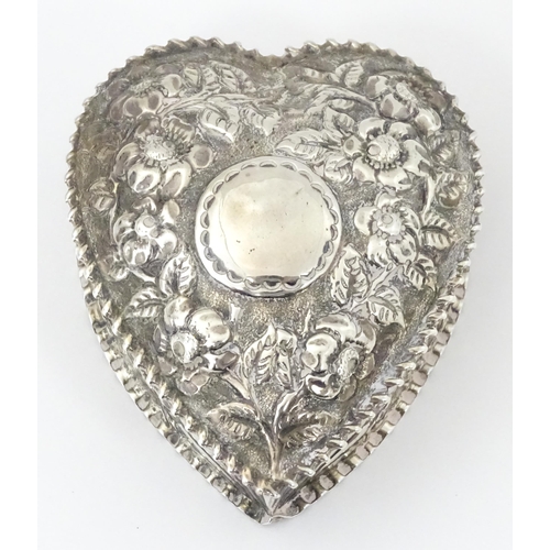 266 - A Victorian silver box of heart form with embossed floral decoration, the lid hinging open to reveal... 