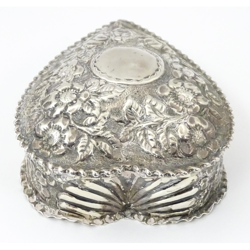 266 - A Victorian silver box of heart form with embossed floral decoration, the lid hinging open to reveal... 