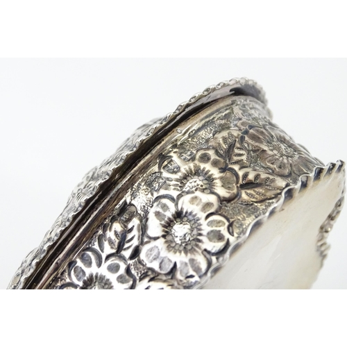 266 - A Victorian silver box of heart form with embossed floral decoration, the lid hinging open to reveal... 