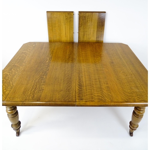 1442 - A late 19thC / early 20thC oak dining table with canted corners raised on turned tapering legs termi... 