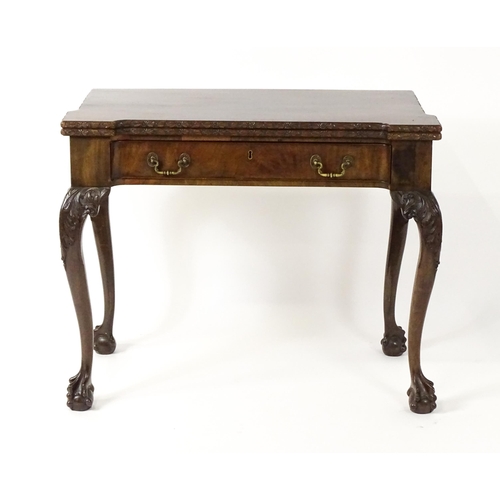 1449 - An Irish Chippendale mahogany card table with a carved inverted breakfront top, opening to show a ba... 