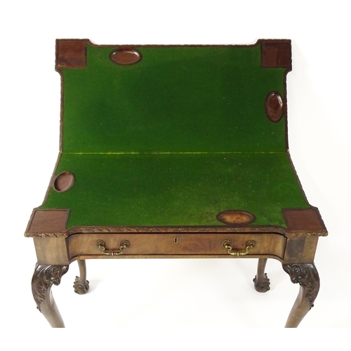 1449 - An Irish Chippendale mahogany card table with a carved inverted breakfront top, opening to show a ba... 