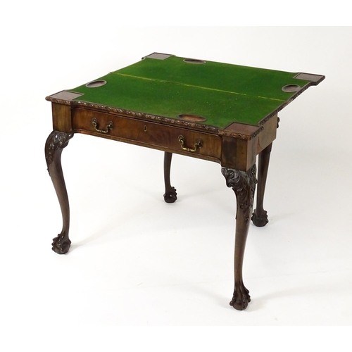 1449 - An Irish Chippendale mahogany card table with a carved inverted breakfront top, opening to show a ba... 