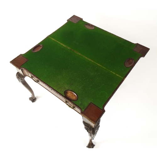 1449 - An Irish Chippendale mahogany card table with a carved inverted breakfront top, opening to show a ba... 