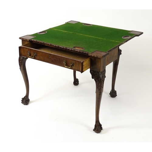 1449 - An Irish Chippendale mahogany card table with a carved inverted breakfront top, opening to show a ba... 