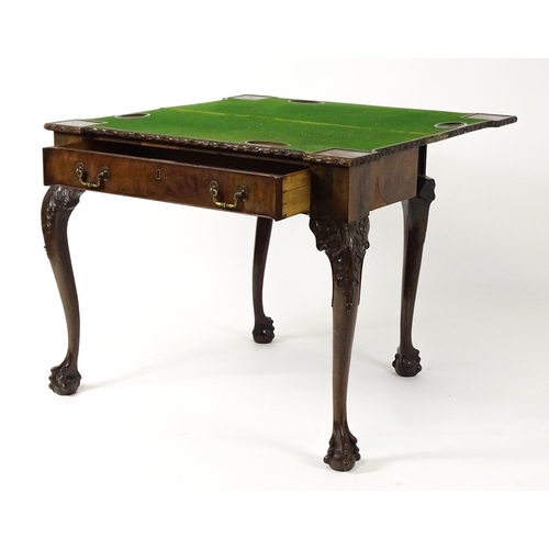 1449 - An Irish Chippendale mahogany card table with a carved inverted breakfront top, opening to show a ba... 