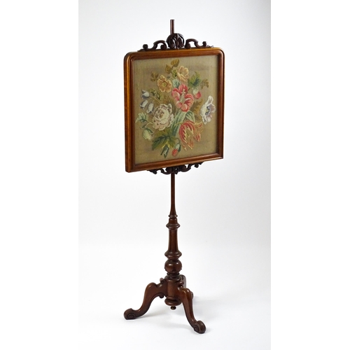 1473 - A late 19thC mahogany pole screen with an embroidered screen surmounted by scrolled carving and rais... 