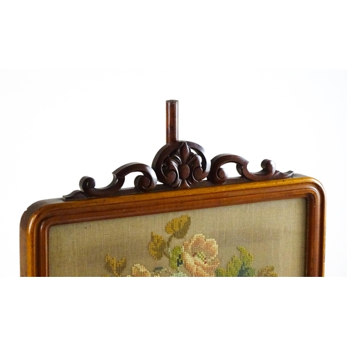 1473 - A late 19thC mahogany pole screen with an embroidered screen surmounted by scrolled carving and rais... 