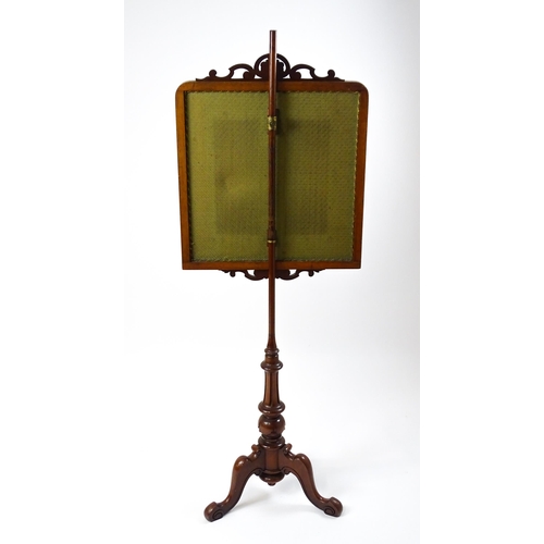 1473 - A late 19thC mahogany pole screen with an embroidered screen surmounted by scrolled carving and rais... 