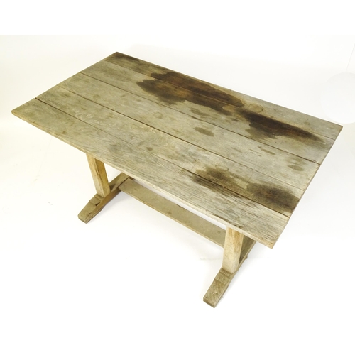 1506 - An early 20thC Heals style oak trestle table with a planked top. 54