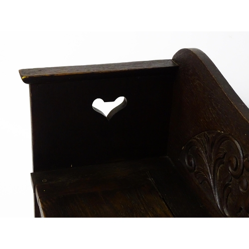 1529 - An early 20thC oak monks bench with pierced heart shaped decoration, having a carved backrest and ap... 