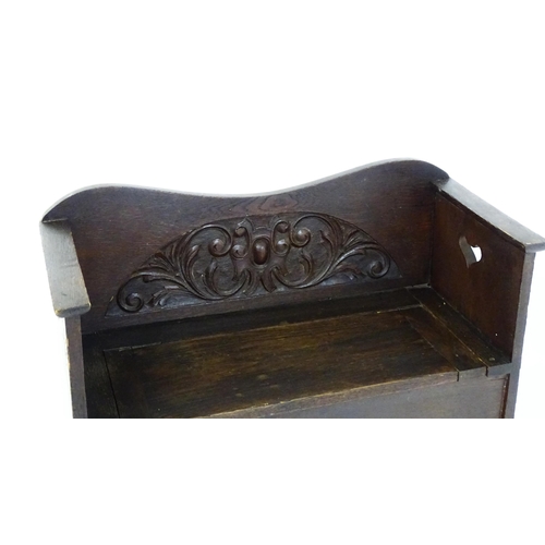 1529 - An early 20thC oak monks bench with pierced heart shaped decoration, having a carved backrest and ap... 