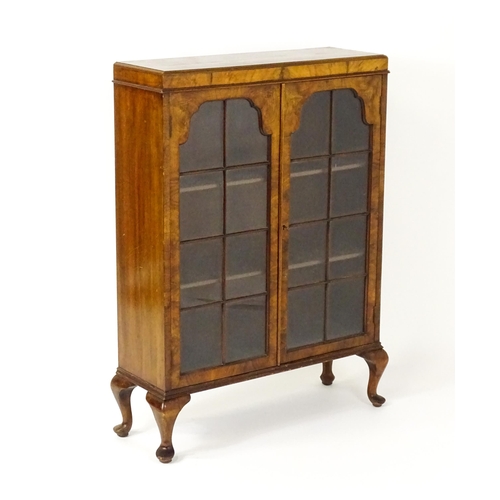 1545 - An early / mid 20thC walnut glazed display cabinet with two astragal glazed doors raised on four cab... 